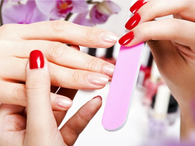 Handen die tijdens een manicure worden gevijld