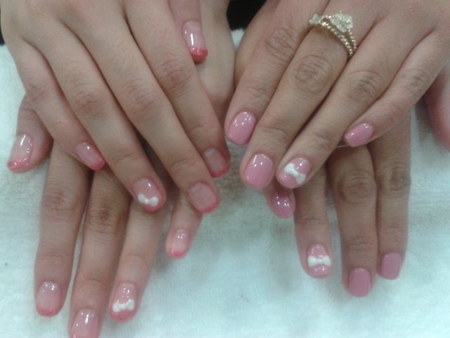 Roze gelakte nagels met een wit strikje als nail-art
